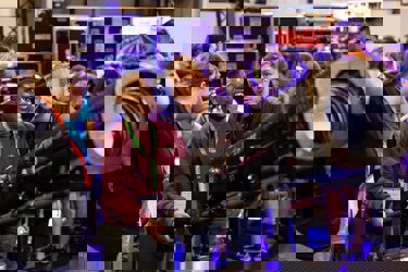 A young person smiling at The Big Bang Fair. Adults are showing them how to operate a theatre light