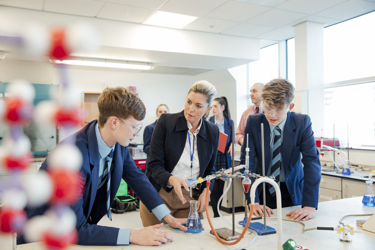School science lab with pupils and teacher conducting an experiment 