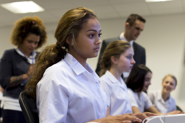 A group of secondary school students and their teacher in a school computer room working