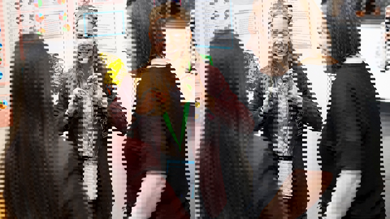 A young person at their Big Bang Competition stand at The Big Bang Fair shows their Competition entry to two visitors