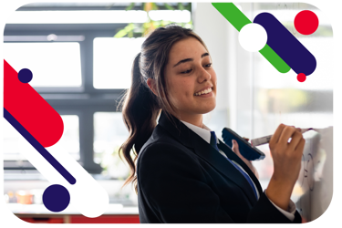 Young person writing on a whiteboard and smiling. They are wearing school uniform. 