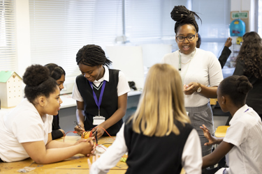 A group of girls doing the Energy Quest fruit experiment in a team as their teacher supports them