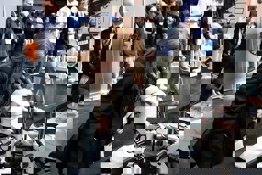 A young person at The Big Bang Fair looks into a microscope as others in the background walk by