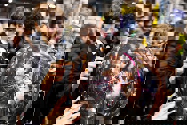 Six hands touch a plasma ball on display at The Big Bang Fair. Four young people are watching the effects.