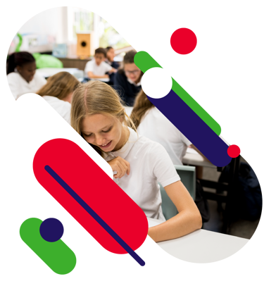 Image of young people working in a school classroom. The focus is on one as they work and smile.