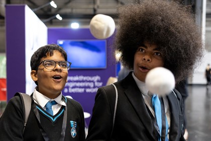 Two young people with expressive faces marvel at a scientific experiment at The Big Bang Fair. In front of them two balls seem to float mid air.