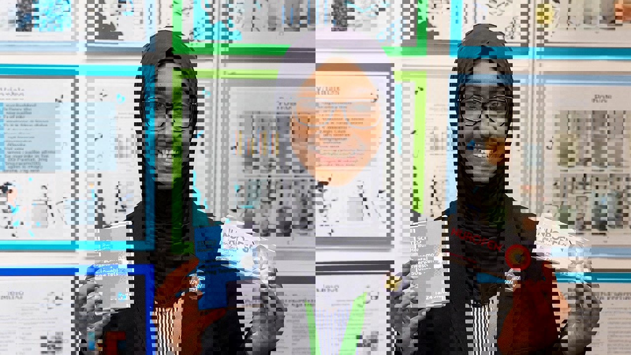 The Big Bang Competition's UK Young Scientist of the Year winner stands and smiles at the camera surrounded by her working boards, photographs and sketches that show how her winning idea developed